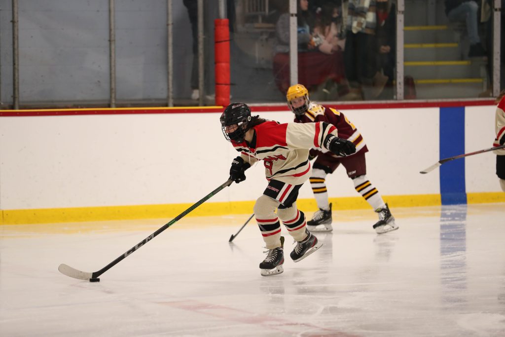Sophomore Reese Pompeo skates through the neutral zone away from 2 defenders. 