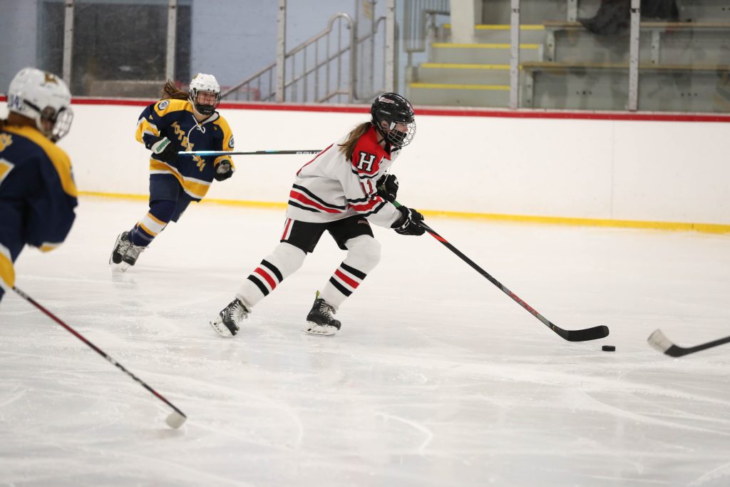 8th grader Julia Baldwin skates through a couple of NDA players to clear the puck out of her end.
