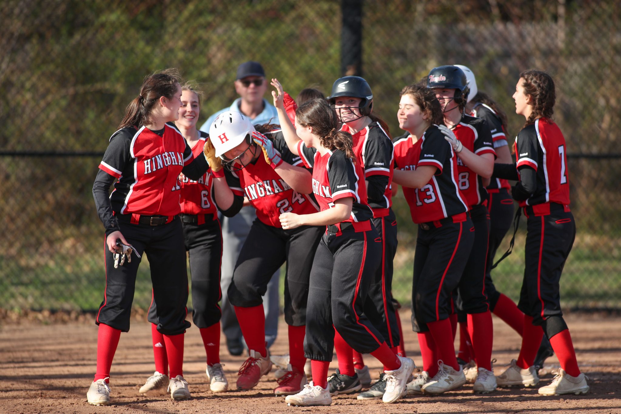 Teammates surround junior Sarah Holler after she belted a 3-run homer in the third inning. 