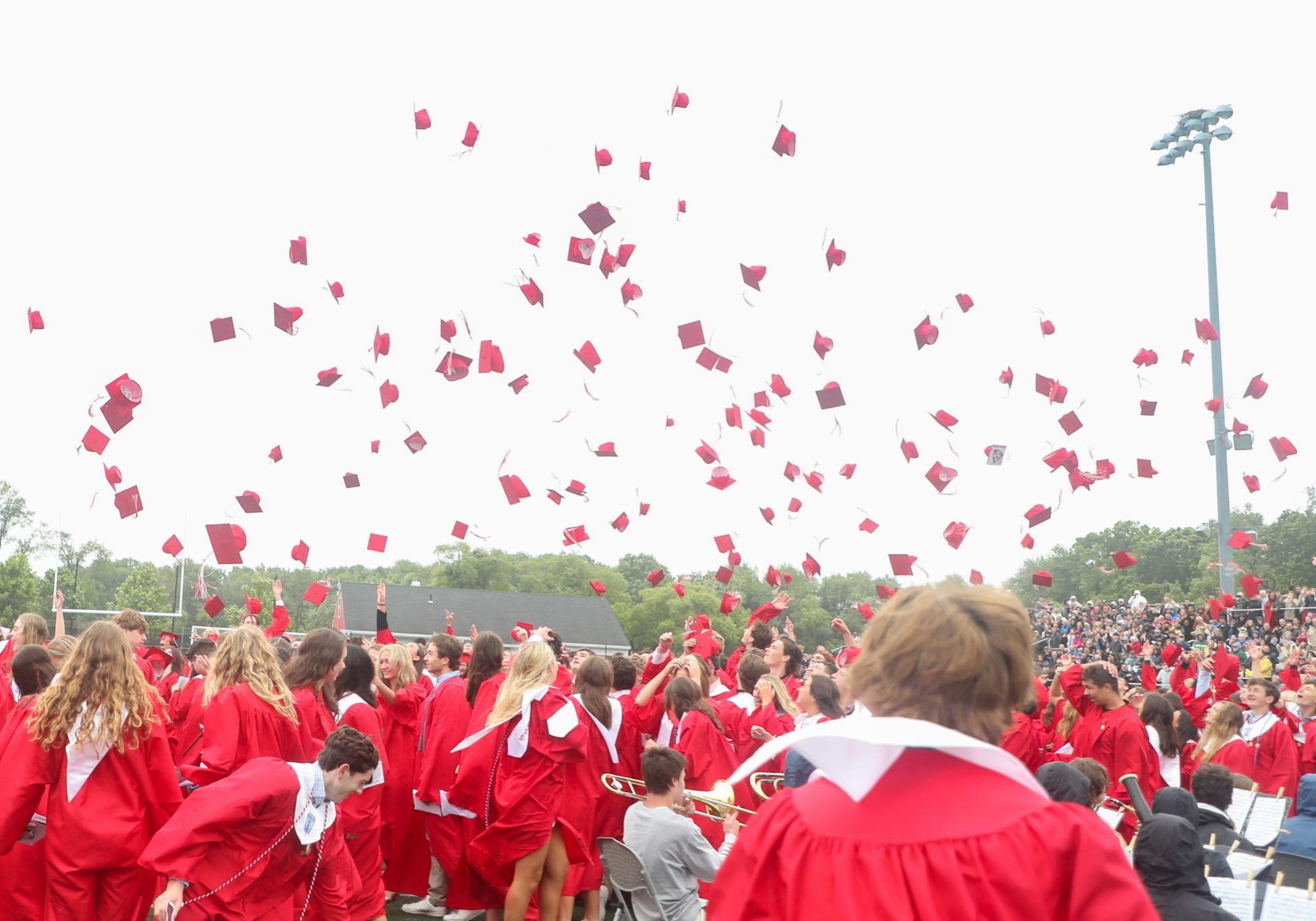 318 graduating seniors of Hingham High School toss their caps in air. 